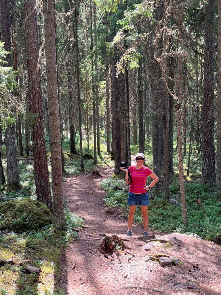 Women in the forest holding a camera in one hand